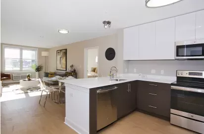 Open-concept apartment kitchen and dining area at One23 Apartments with quartz countertops, stainless steel appliances, and wood-style flooring