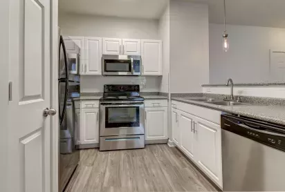 Modern kitchen with stainless steel appliances, granite countertops, and white cabinetry at The Saulet Apartments in New Orleans, LA.