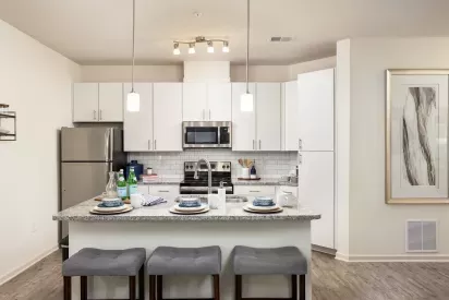 Spacious kitchen with island seating, pendant lighting, and subway tile backsplash at Avery Turkey Creek Apartments.