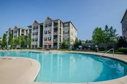 Exterior view of the apartment buildings surrounding a large pool and sun deck area.