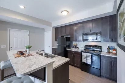 Modern kitchen at Victoria Manor Gardens featuring sleek granite countertops and black kitchen appliances.