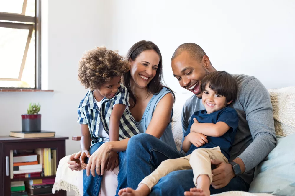 Two parents in a living room on a couch with two children on their laps