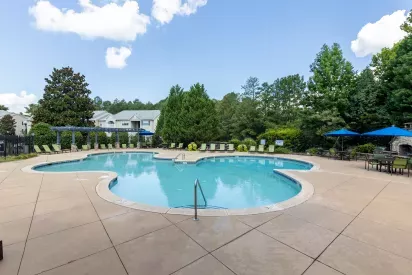 Sparkling swimming pool with lounge chairs under pergolas for residents to enjoy.
