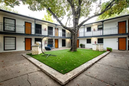 Open courtyard with large tree and bright greenery area for residents to enjoy.