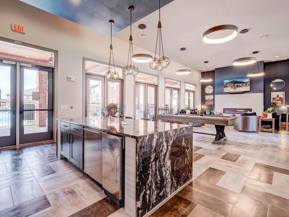 Modern common room with a marble island, tiled floor, pool table, fireplace, and flat-screen TV.