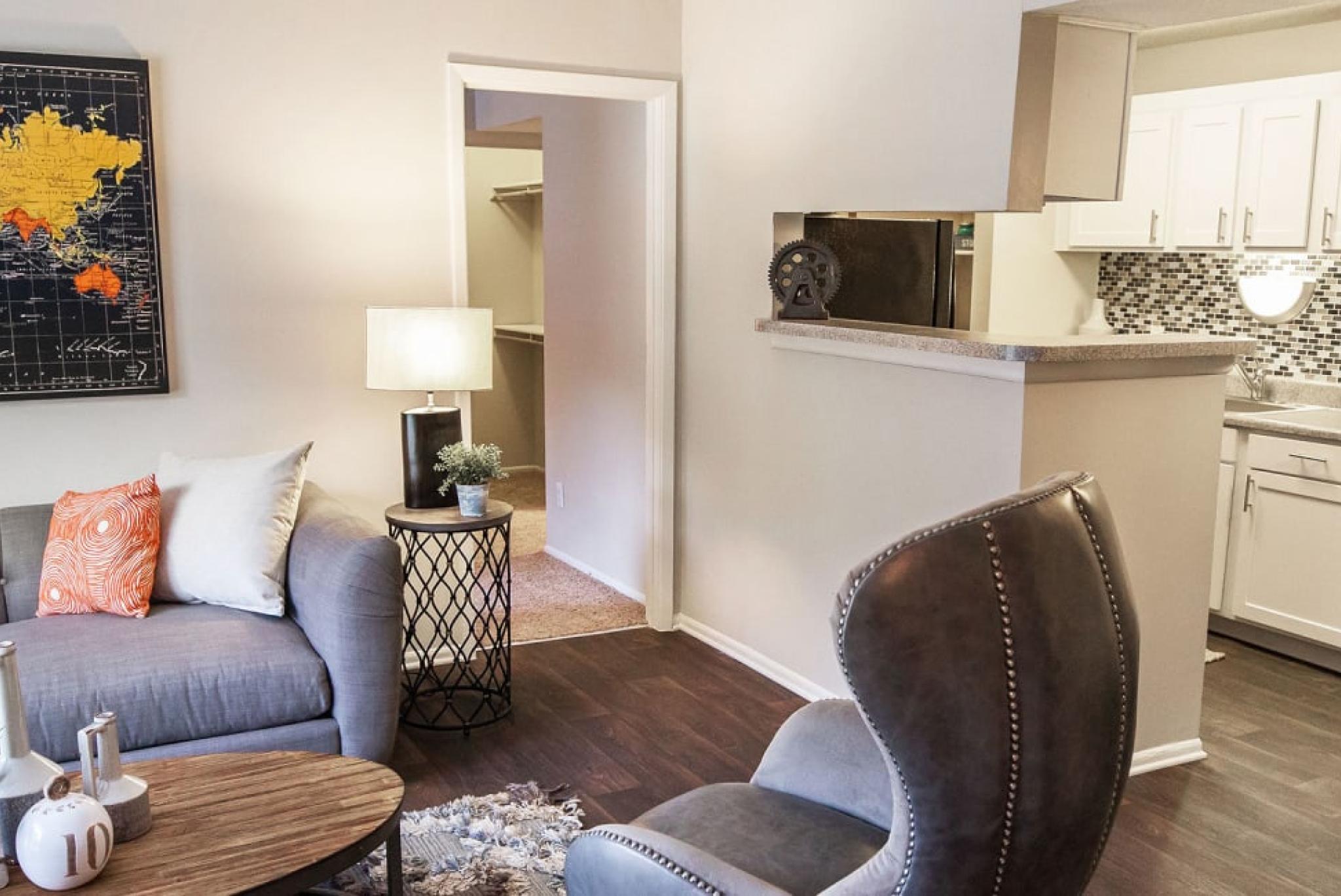 Cozy studio apartment featuring a comfortable bed with decorative pillows, a small dining area, and an efficient kitchen, with vibrant artwork adding a personal touch to the living space.
