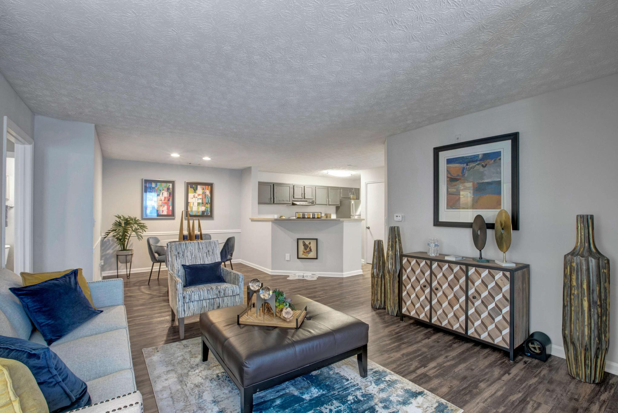 Stylish and open-concept living and dining area featuring modern décor, wood-style flooring, and a view into the sleek, updated kitchen with stainless steel appliances.