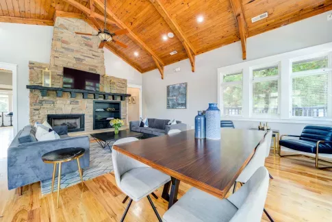 Spacious community lounge featuring a stone fireplace, vaulted wooden ceilings, and modern furnishings, creating a cozy and inviting atmosphere for residents to relax or socialize.