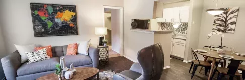 Cozy studio apartment featuring a comfortable bed with decorative pillows, a small dining area, and an efficient kitchen, with vibrant artwork adding a personal touch to the living space.