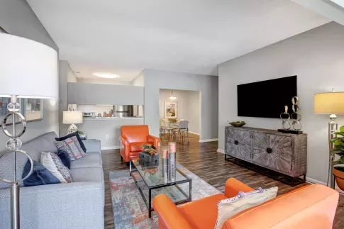 Living area at Amber Chase Apartments viewed from the entrance, with bright orange chairs and modern decor.