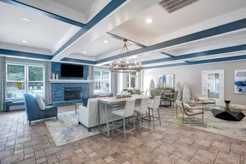 Clubhouse interior with coffered ceiling, fireplace, modern furniture, and large TV.