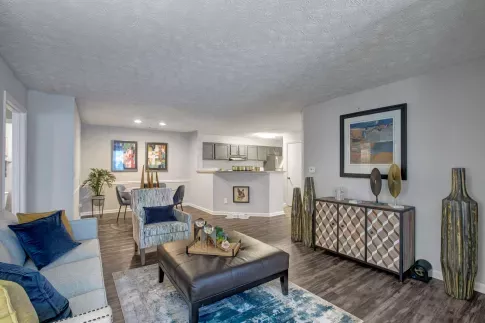 Stylish and open-concept living and dining area featuring modern décor, wood-style flooring, and a view into the sleek, updated kitchen with stainless steel appliances.