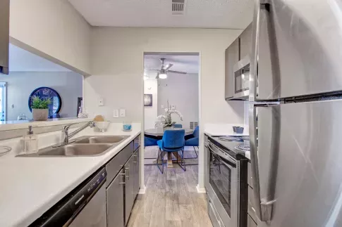 Bright, contemporary kitchen with sleek granite-style countertops, modern appliances, and white cabinetry. The space is well-lit with recessed lighting and natural light from a nearby window, creating a fresh and inviting atmosphere perfect for cooking and entertaining.