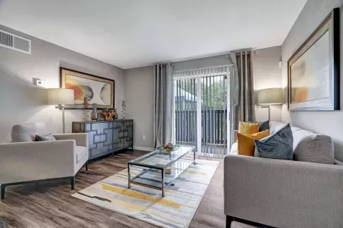 Living room with neutral-toned furniture, large artwork, and sliding glass doors with natural light.