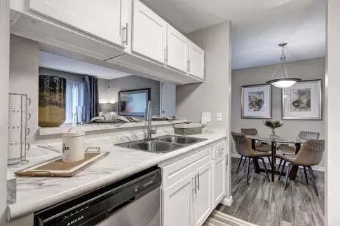 Kitchen with marbled countertops, white cabinets, and view into dining area with modern decor