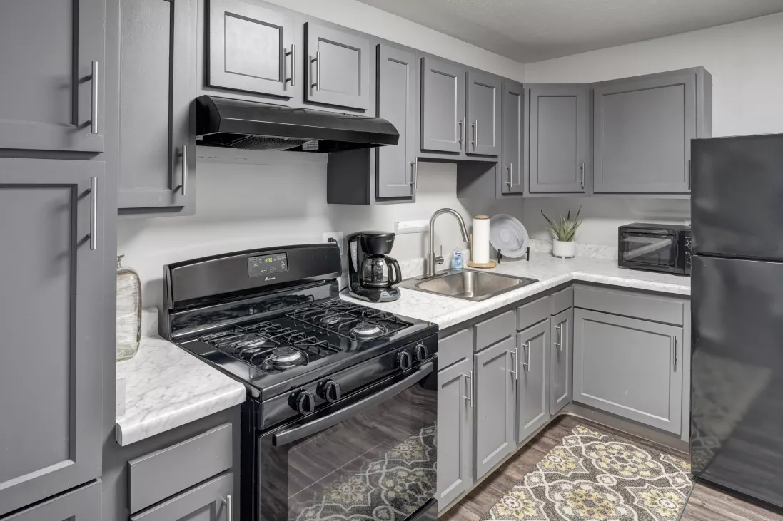 U-shaped kitchen with dark gray cabinets, white countertops, black stove, microwave, and fridge.