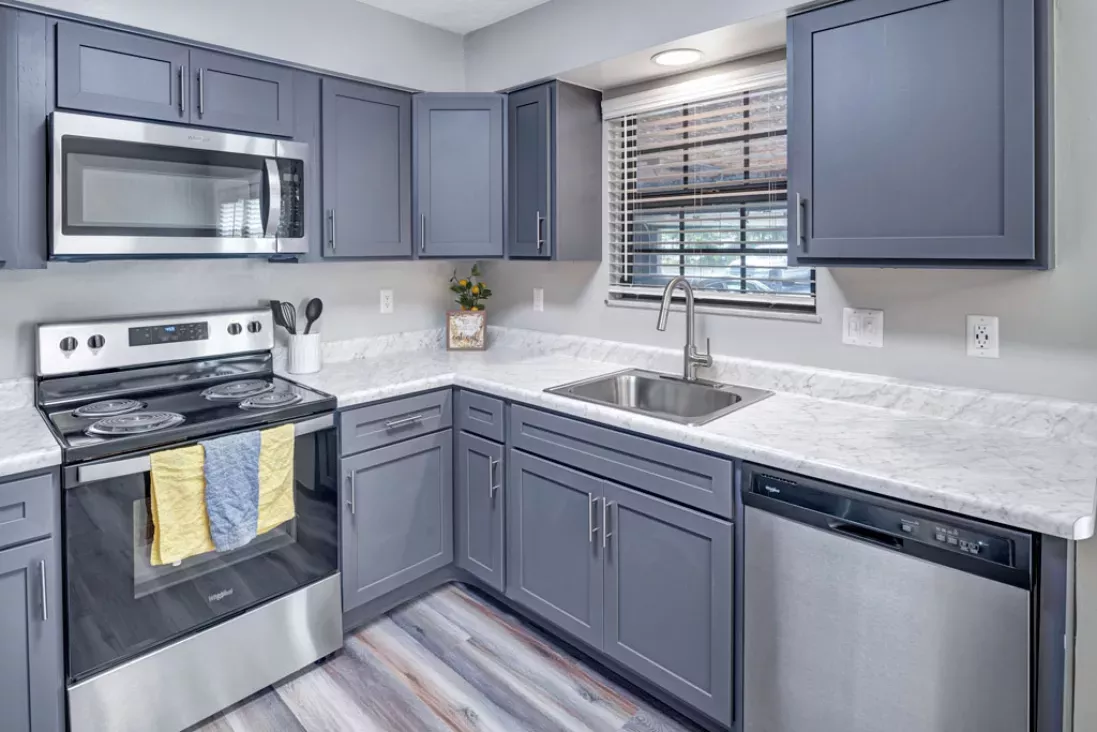 Modern kitchen with gray cabinets, light countertops, and stainless steel appliances. Window above sink.