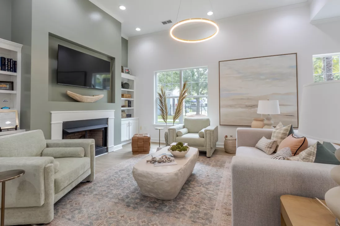 Modern living room with a green accent wall, fireplace, TV, white sofa, light green chairs, and abstract art.