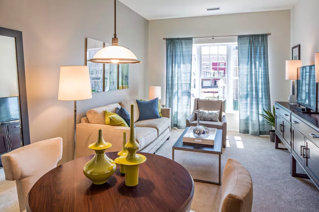 Bright and cozy living room in a model apartment at The Grove Somerset Apartments, showcasing modern furniture and large windows.