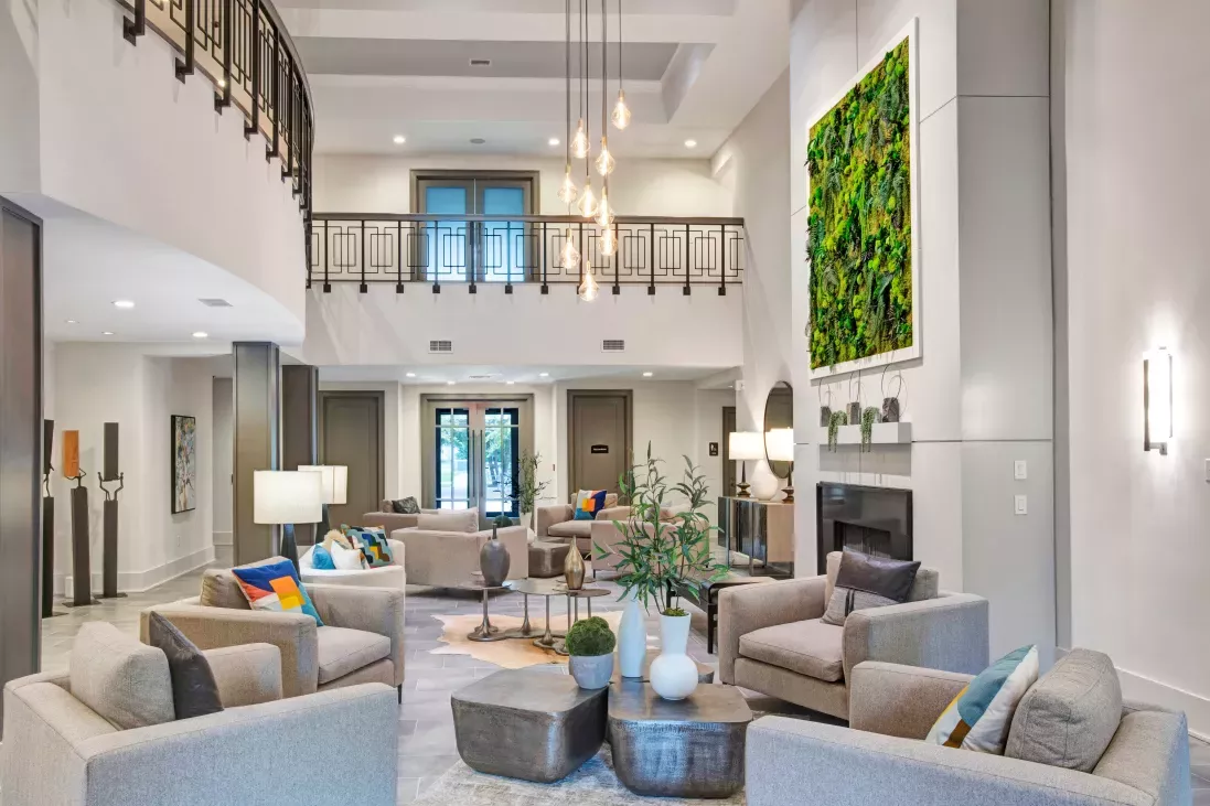Elegant two-story lobby at The Grove Somerset Apartments featuring modern furnishings, vibrant green living wall art, and a sophisticated chandelier.