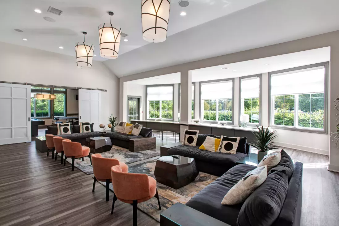 Spacious resident lounge with stylish seating, large windows for natural light, and contemporary design at The Grove Somerset Apartments.