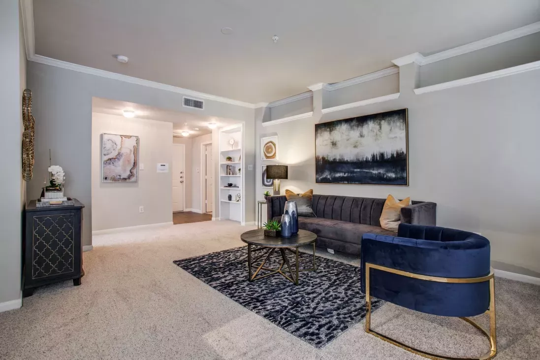 Spacious living room with plush carpet, sophisticated furnishings, and decorative accents, providing a warm and inviting atmosphere at Arboretum Estates.