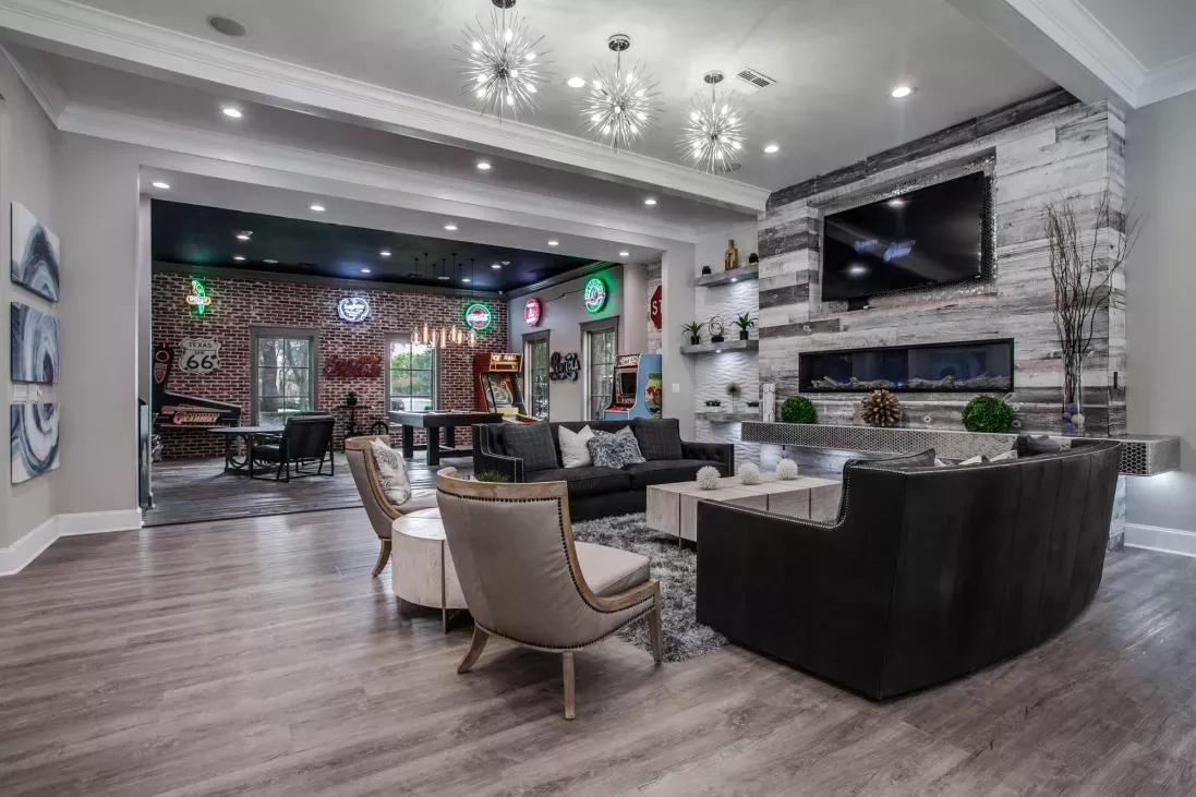 Stylish community lounge featuring contemporary furniture, vibrant neon wall art, and a cozy fireplace, perfect for social gatherings at Arboretum Estates.