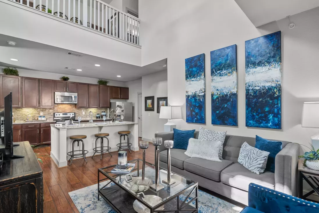 A spacious living area with a kitchen in the background, showcasing an open-concept design at Arrabella Apartments.