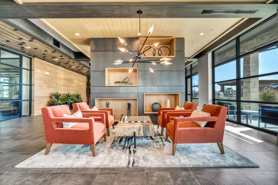 A stylish lounge area featuring orange armchairs, a central coffee table, and contemporary décor.