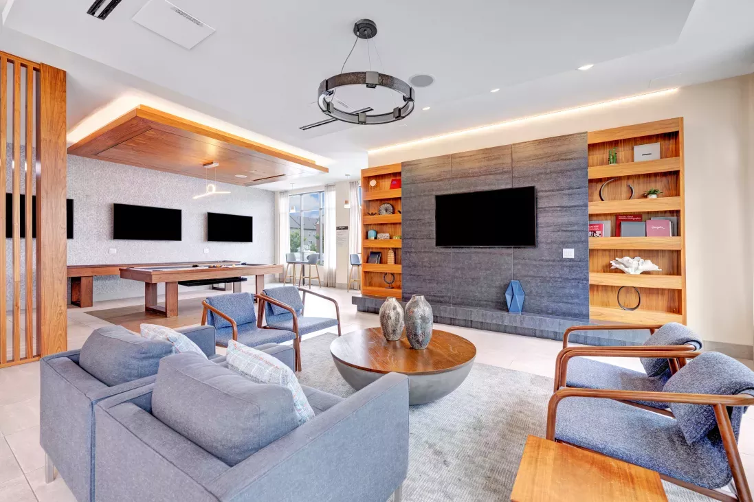A sophisticated resident lounge featuring plush seating, a billiards table, mounted flat-screen TVs, and sleek modern décor, designed for comfort and socializing.
