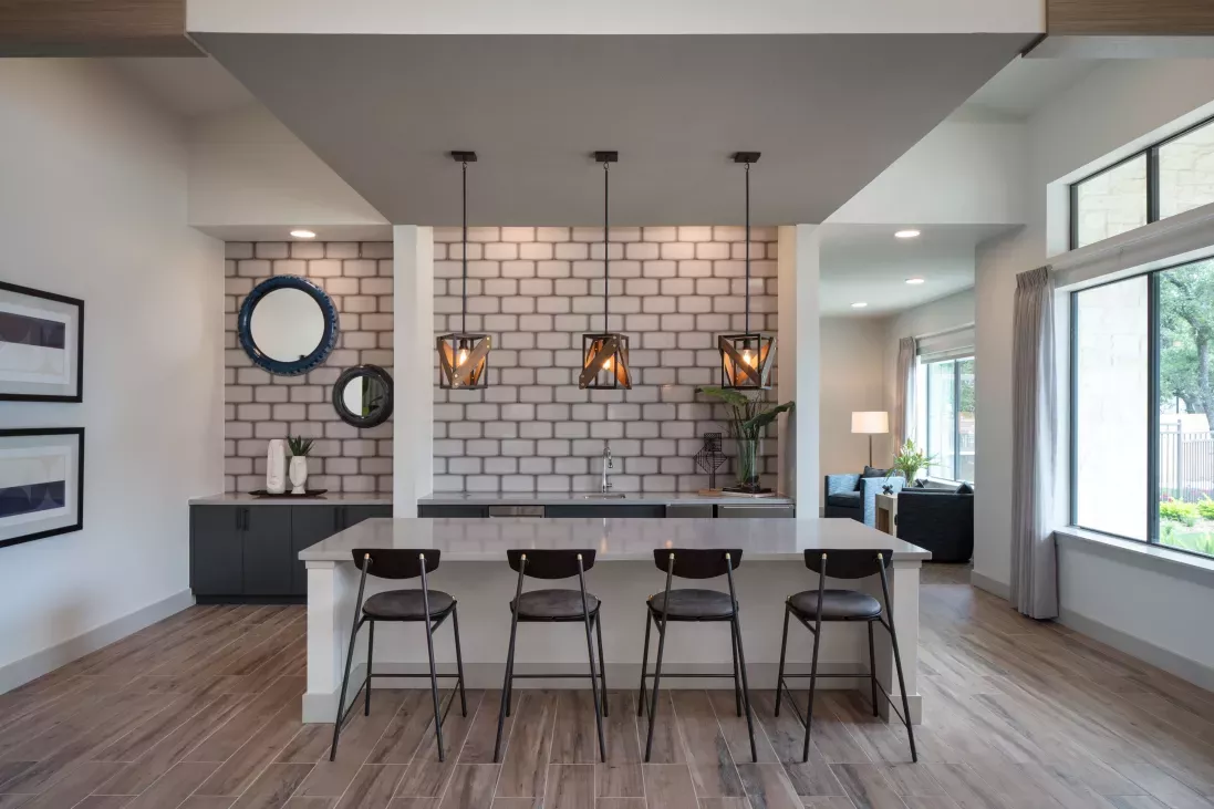 A stylish resident lounge with a sleek bar area, pendant lighting, and contemporary decor offers a sophisticated space for socializing and relaxation.