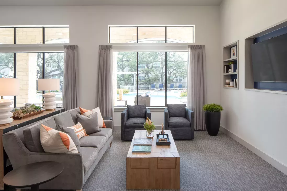 A cozy seating area in the clubhouse overlooks the pool, with large windows bringing in natural light and providing a comfortable, stylish space for residents.