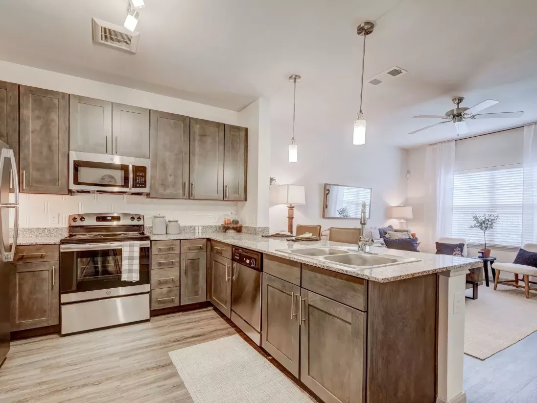 "Contemporary kitchen in an apartment at The Emerson at Forney with granite countertops, stainless steel appliances, and pendant lighting."