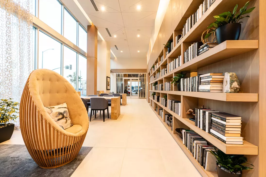 Inviting library and co-working space at The Linden Luxury Apartments with floor-to-ceiling bookshelves, cozy seating, and abundant natural light.