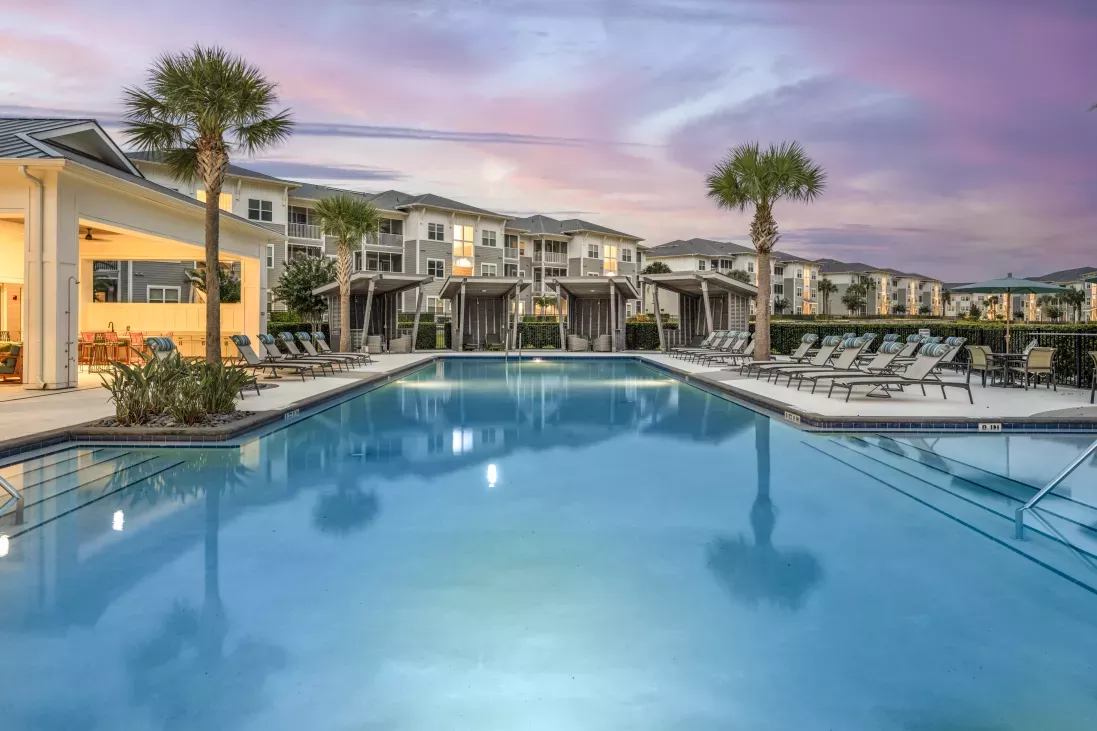 Sparkling, resort style swimming pool with twilight setting. Ample seating for residents to enjoy.