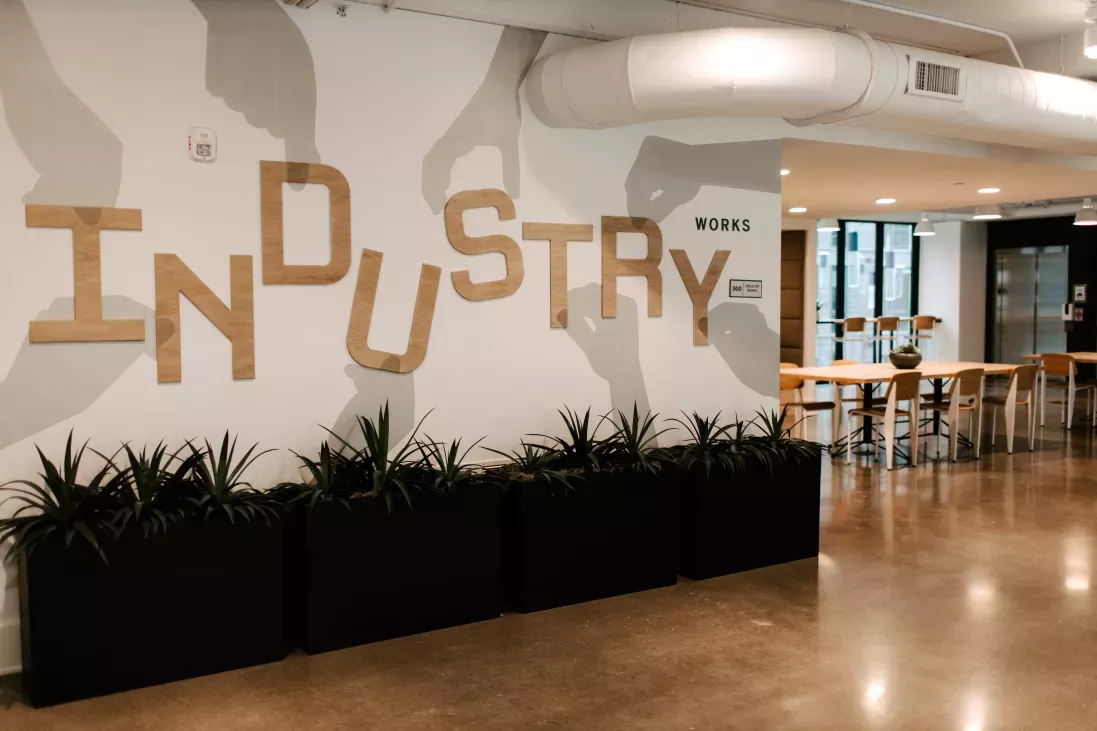 A stylish coworking space in Industry Columbus Apartments with a bold "Industry Works" wall design, contemporary seating, and an open-concept layout for productivity and collaboration.