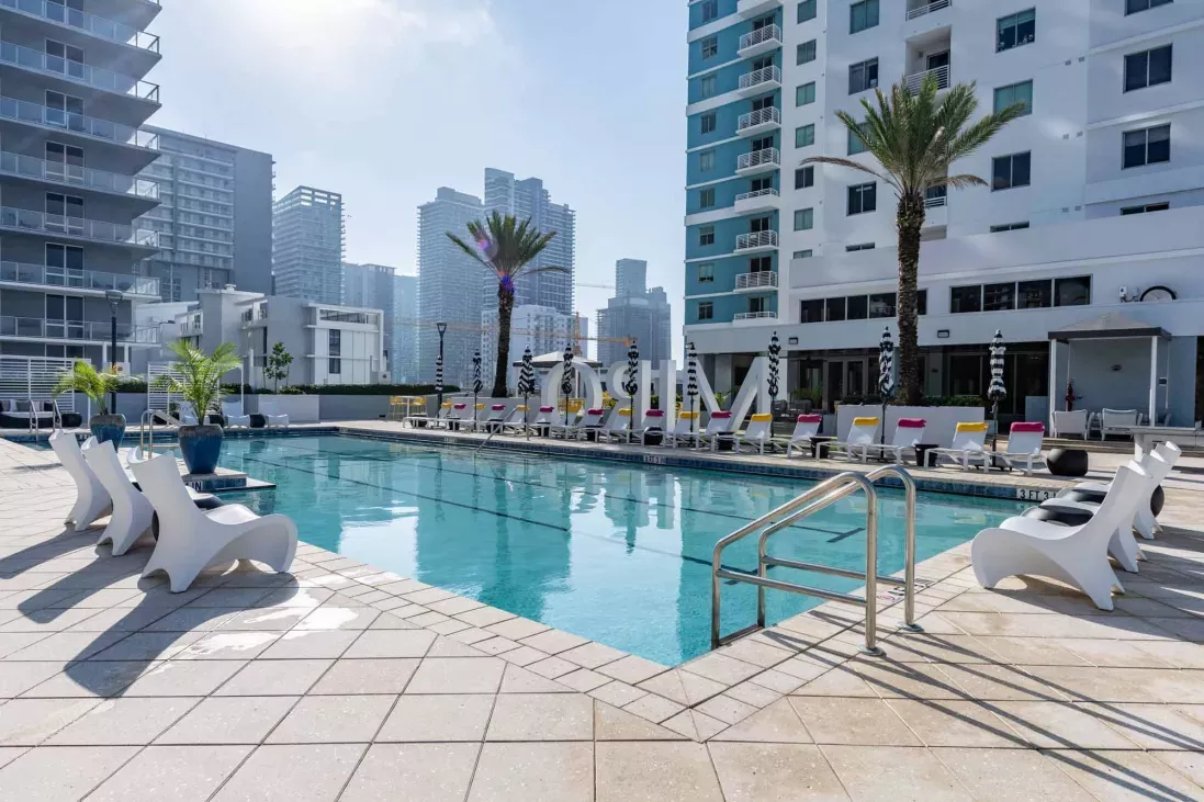 Sparkling outdoor pool surrounded by lounge chairs and palm trees.