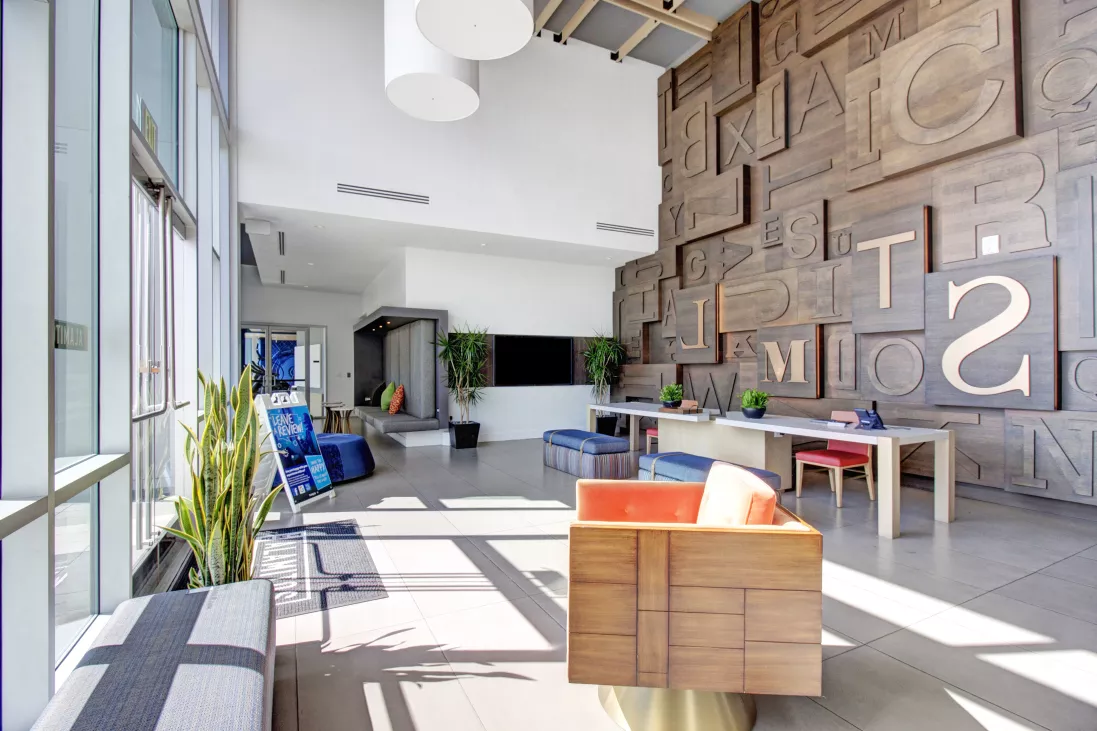 Bright, modern lobby with a tall accent wall made of wooden blocks with embossed letters and numbers, contemporary furniture.