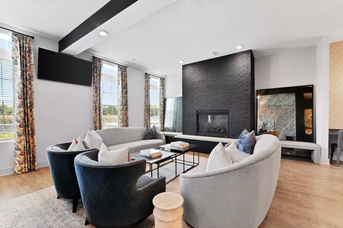 Modern living room with a black tiled fireplace, two gray sofas, and two dark blue armchairs.