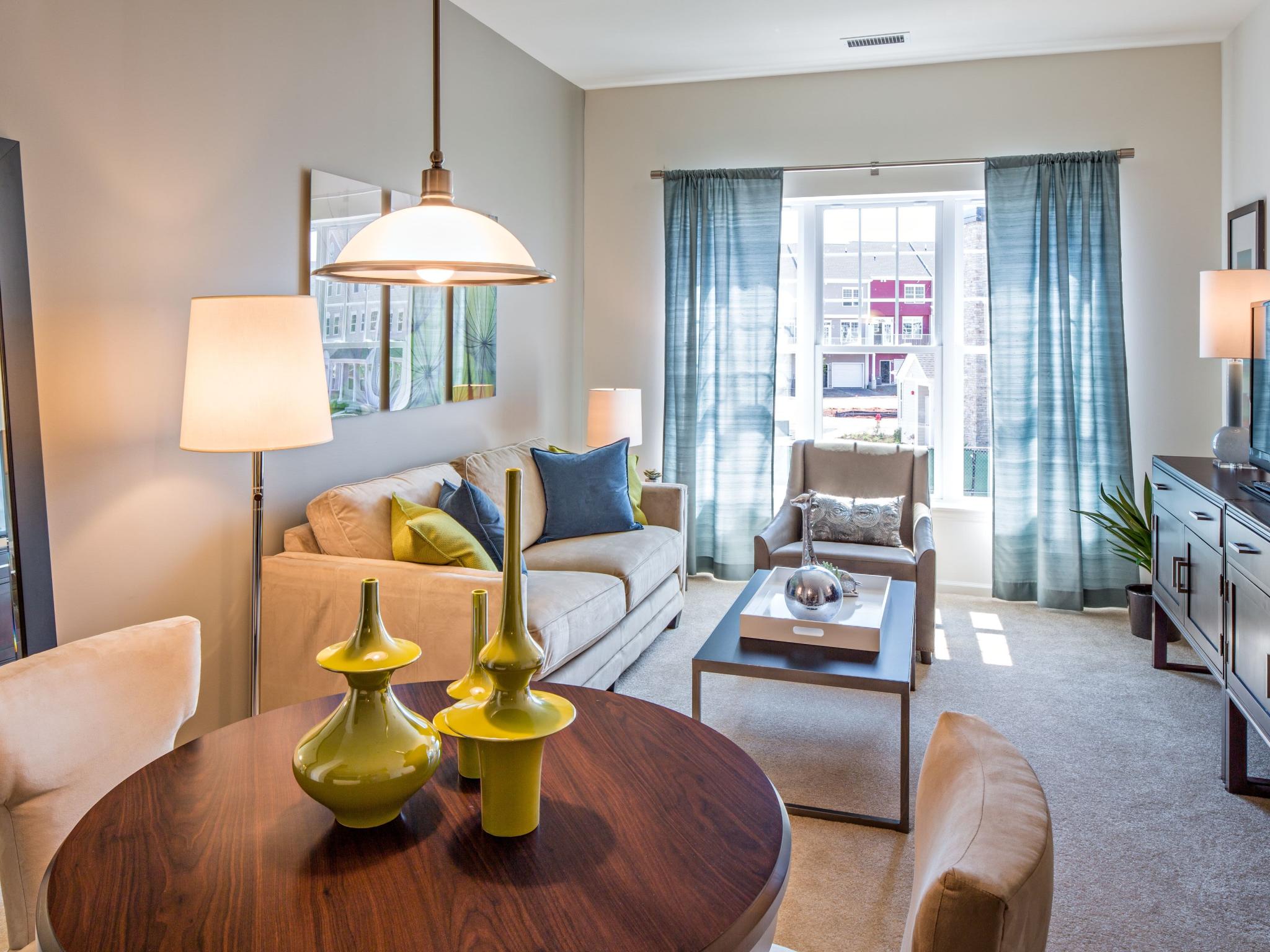Bright and cozy living room in a model apartment at The Grove Somerset Apartments, showcasing modern furniture and large windows.