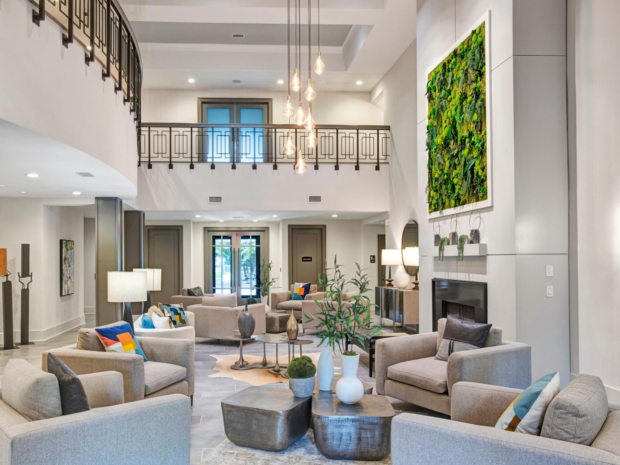 Elegant two-story lobby at The Grove Somerset Apartments featuring modern furnishings, vibrant green living wall art, and a sophisticated chandelier.