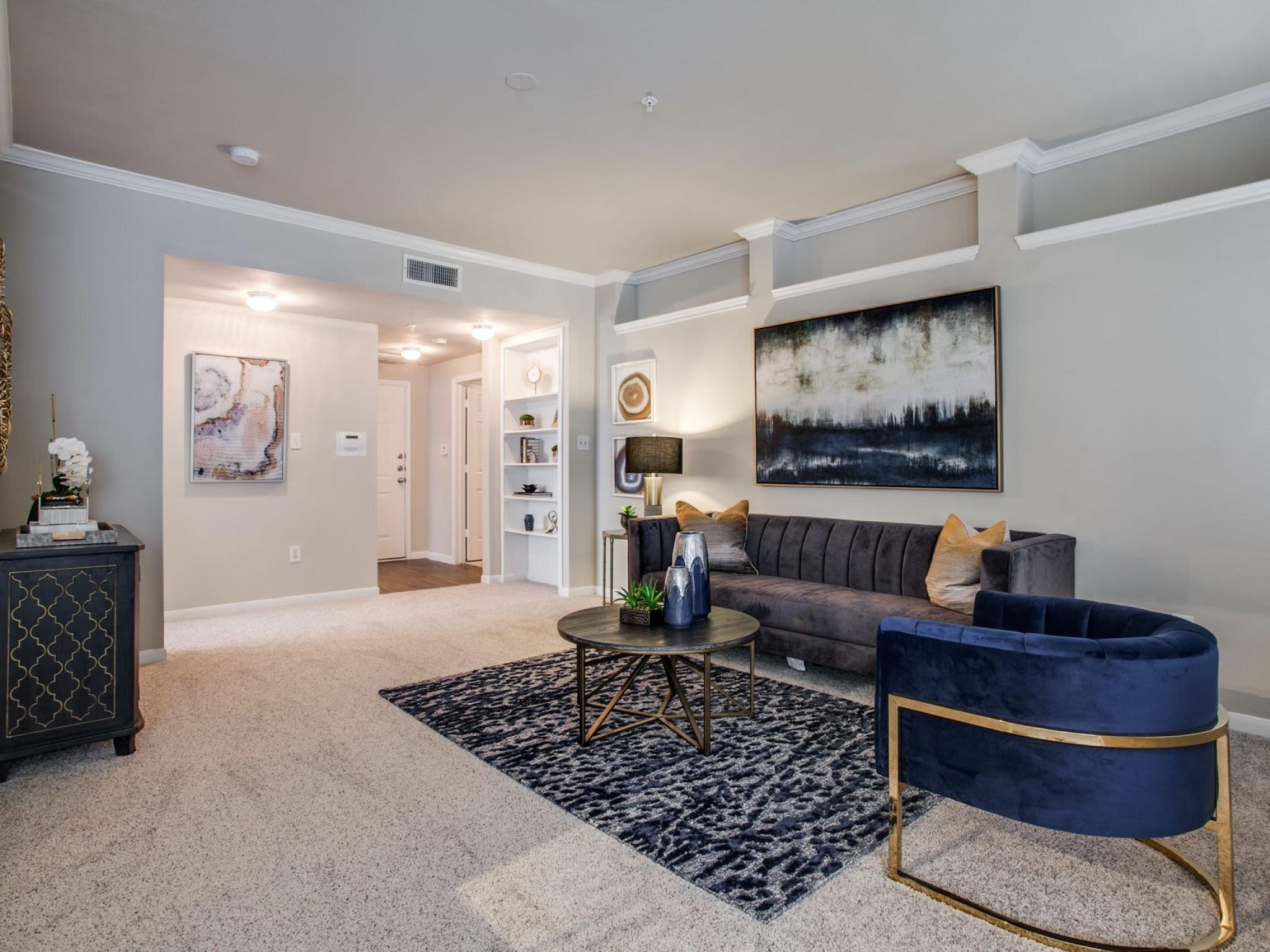 Spacious living room with plush carpet, sophisticated furnishings, and decorative accents, providing a warm and inviting atmosphere at Arboretum Estates.