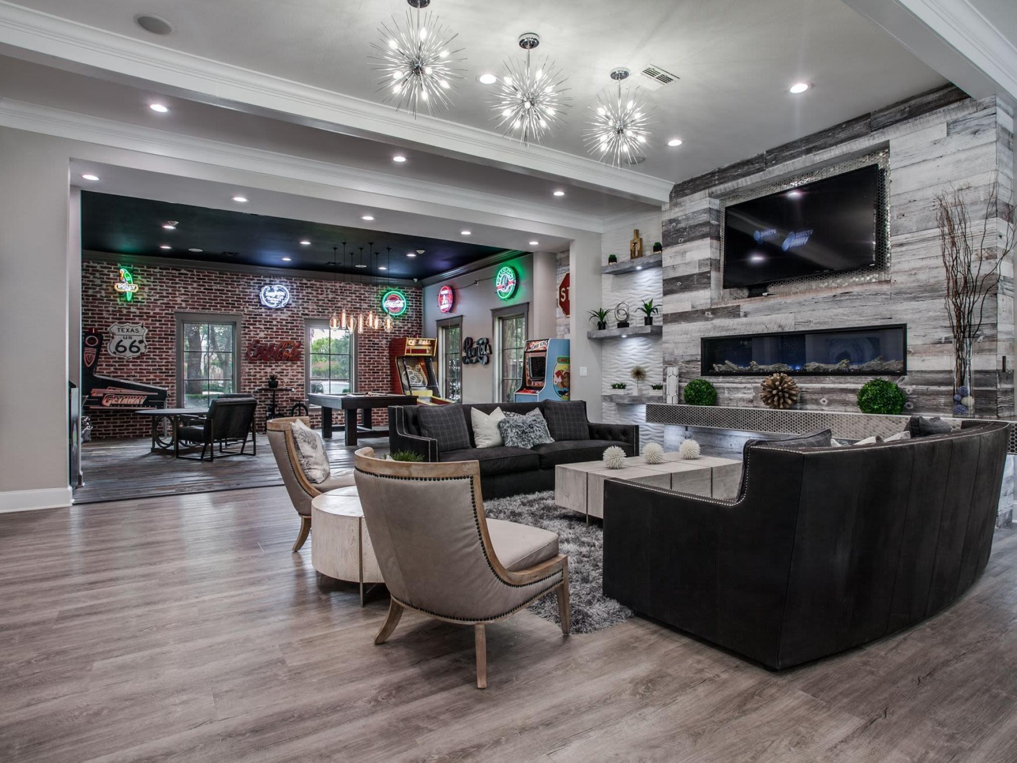Stylish community lounge featuring contemporary furniture, vibrant neon wall art, and a cozy fireplace, perfect for social gatherings at Arboretum Estates.