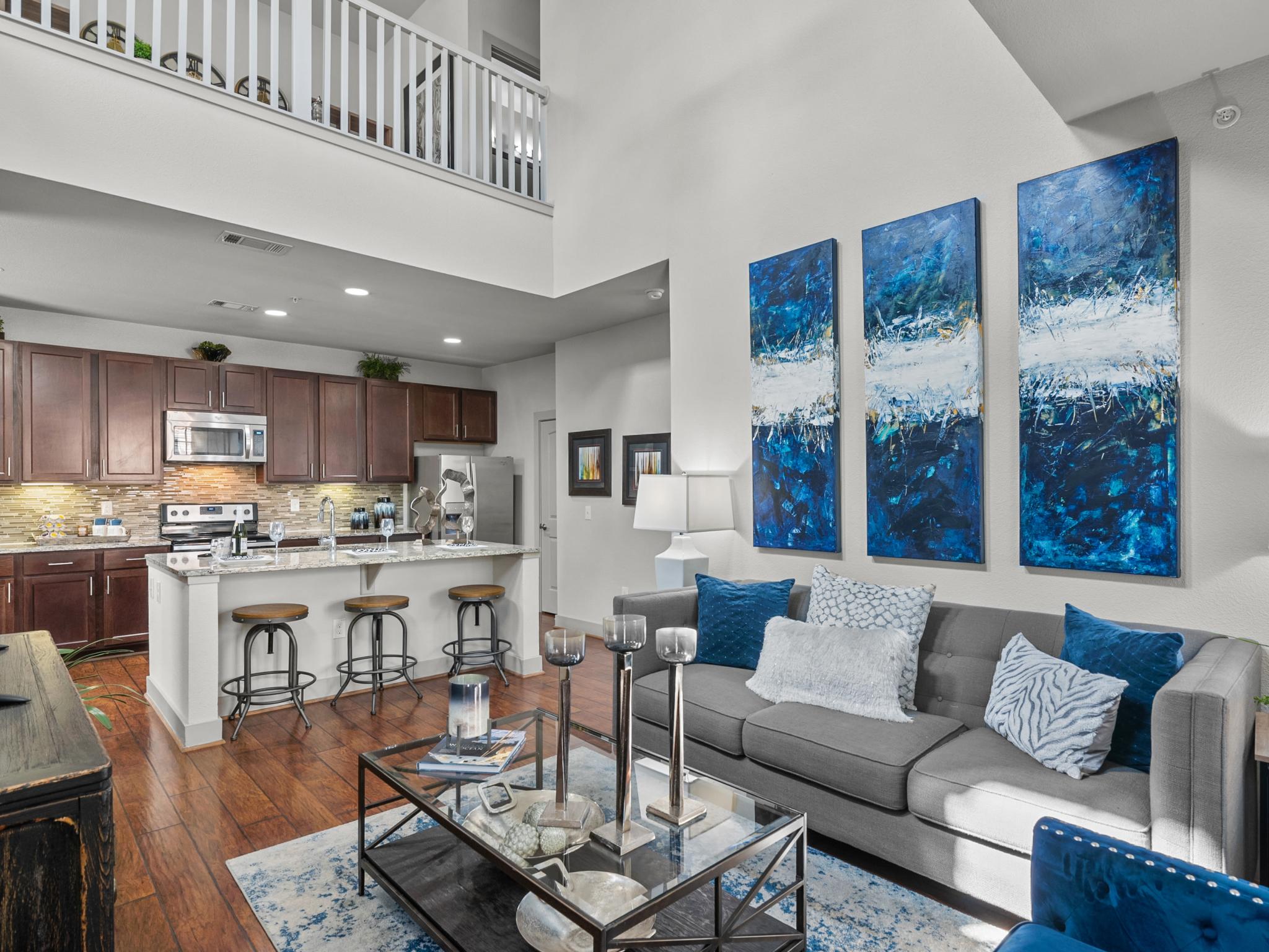 A spacious living area with a kitchen in the background, showcasing an open-concept design at Arrabella Apartments.