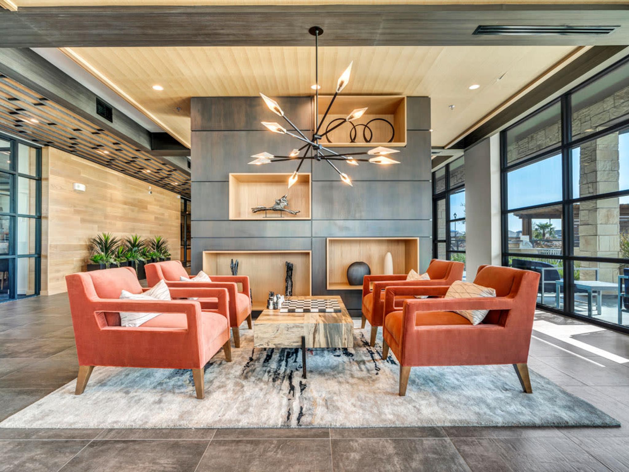 A stylish lounge area featuring orange armchairs, a central coffee table, and contemporary décor.