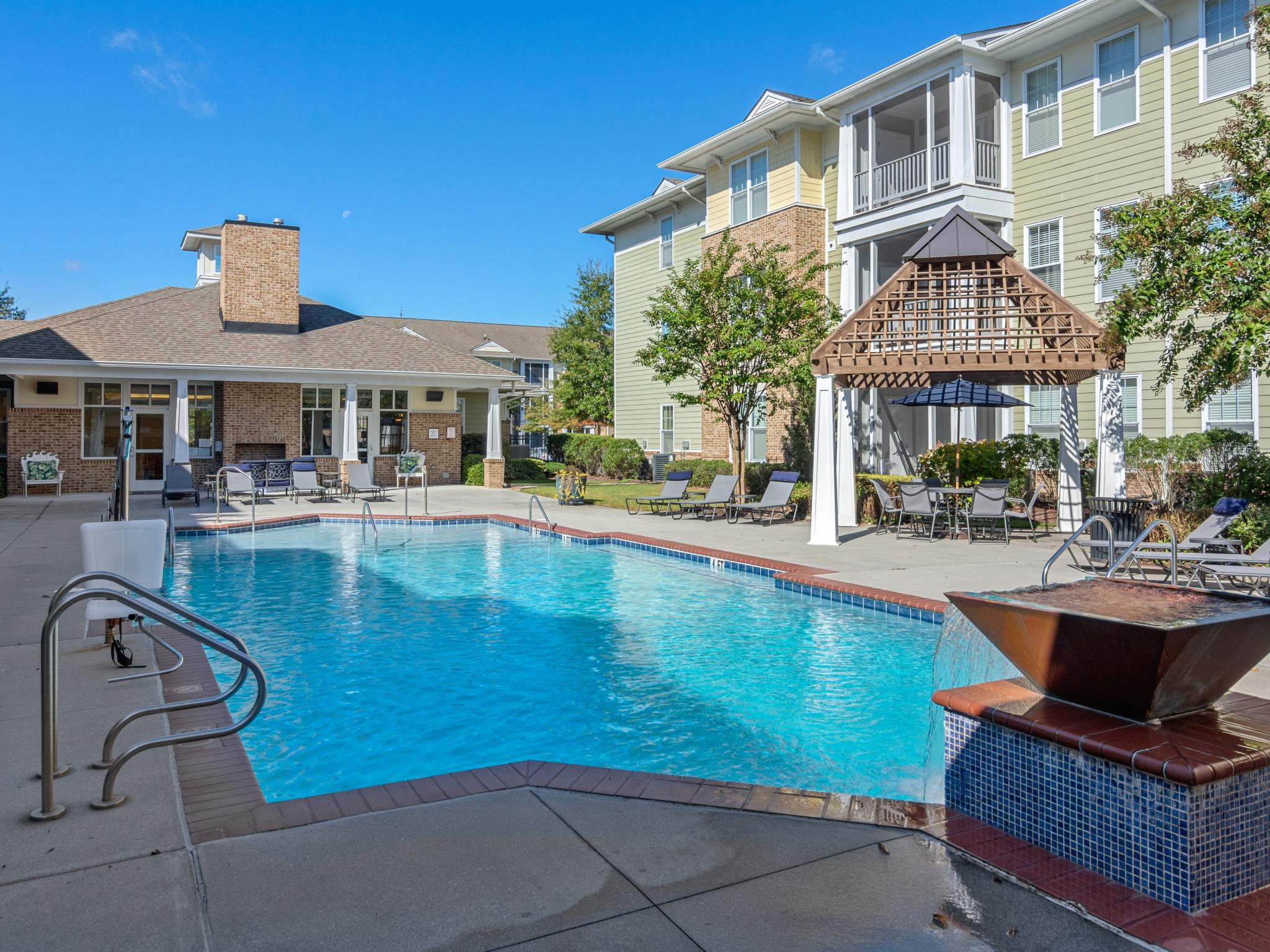 A sparkling outdoor pool with a water feature, surrounded by lounge chairs and a charming gazebo for shaded seating.