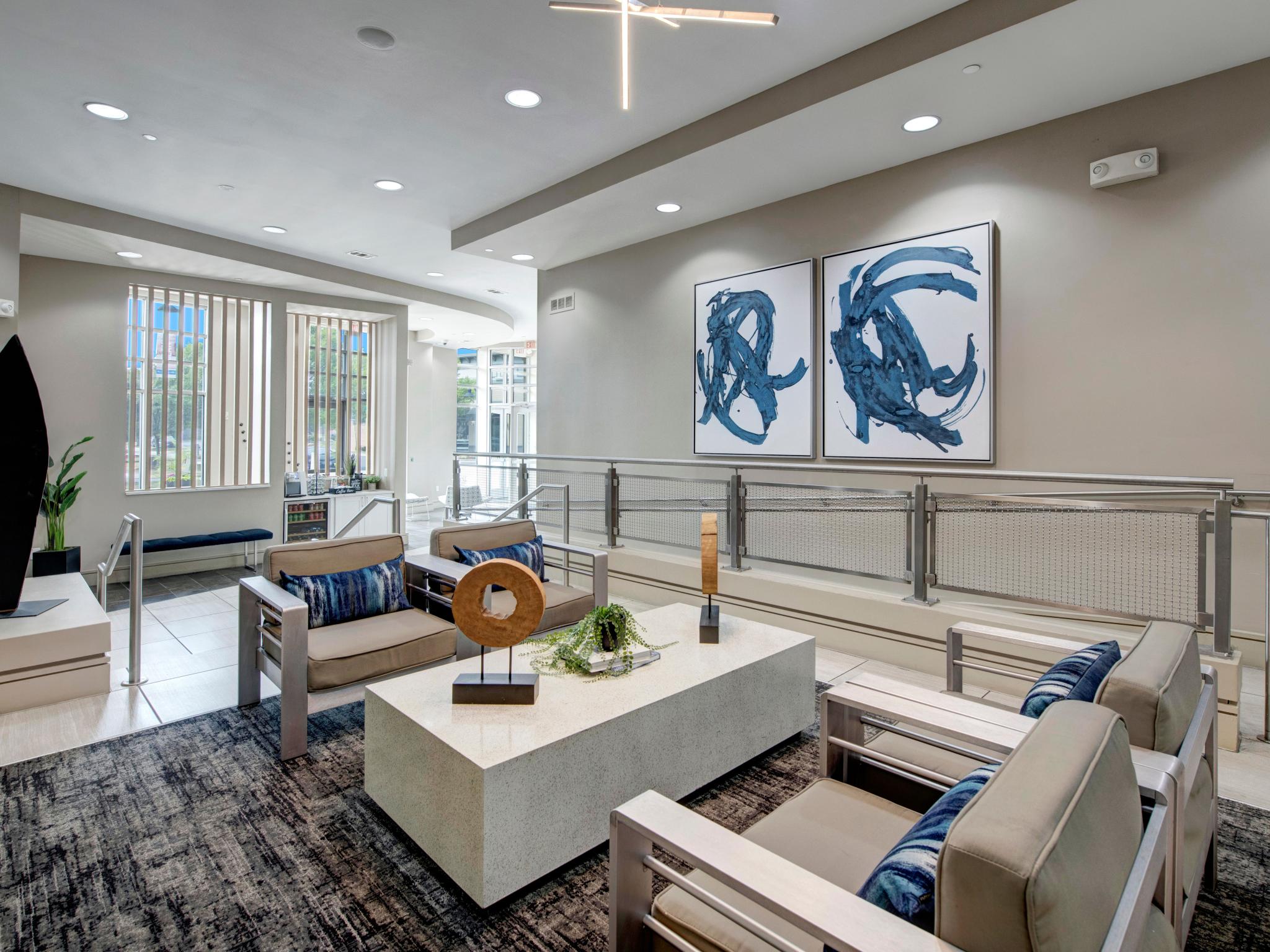 A modern seating area with sleek furniture, a large coffee table, and abstract blue artwork on the wall.