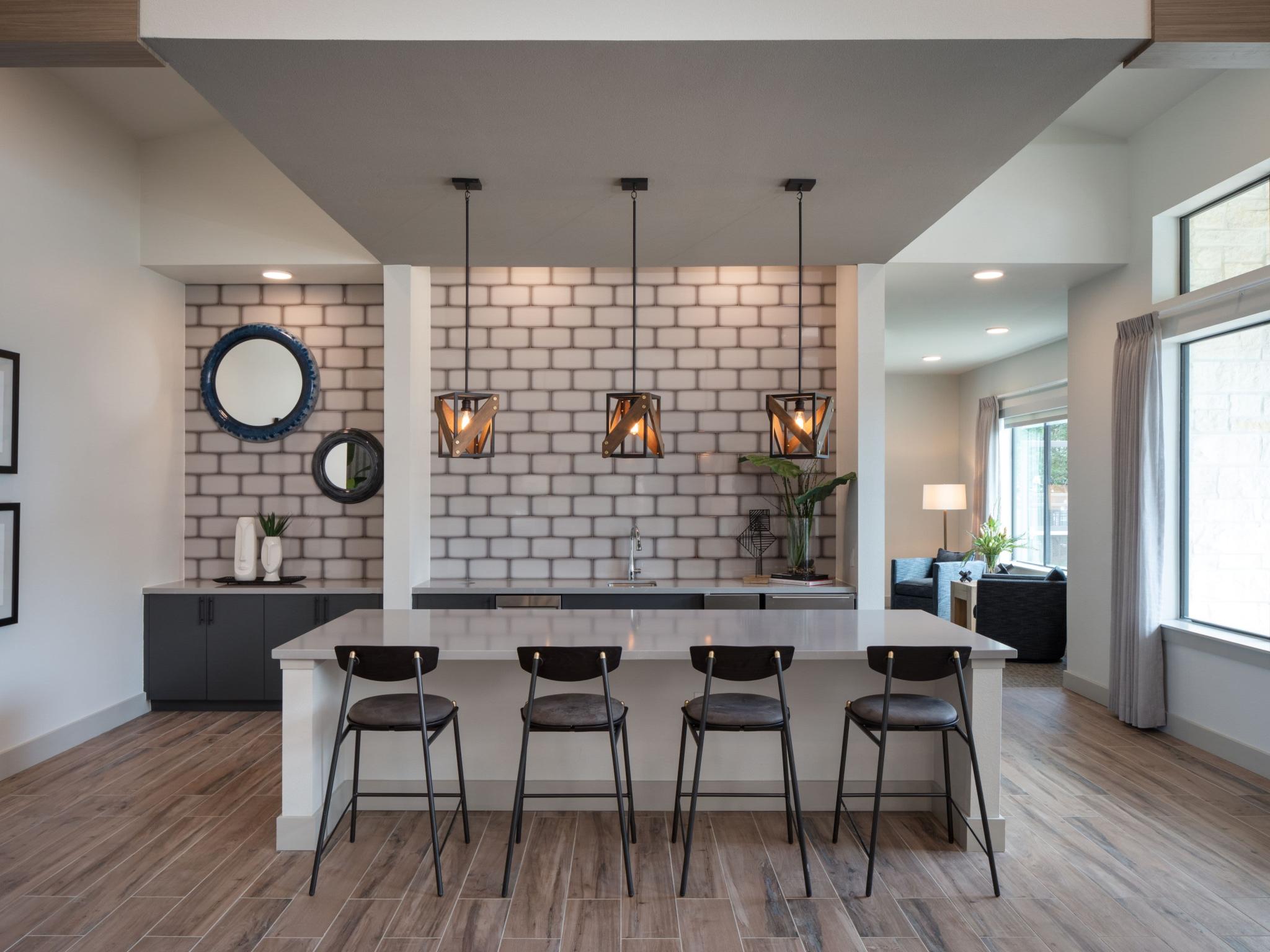 A stylish resident lounge with a sleek bar area, pendant lighting, and contemporary decor offers a sophisticated space for socializing and relaxation.