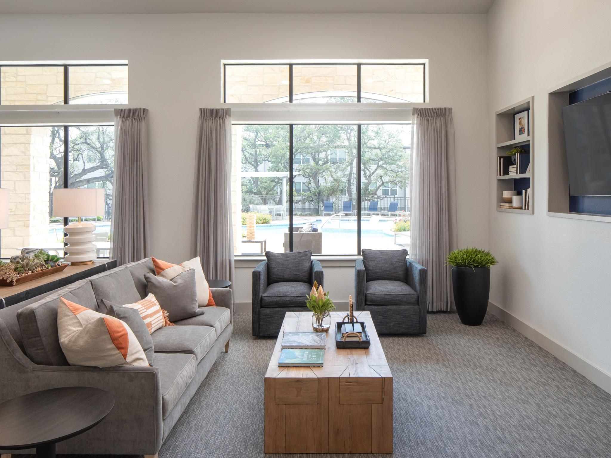 A cozy seating area in the clubhouse overlooks the pool, with large windows bringing in natural light and providing a comfortable, stylish space for residents.