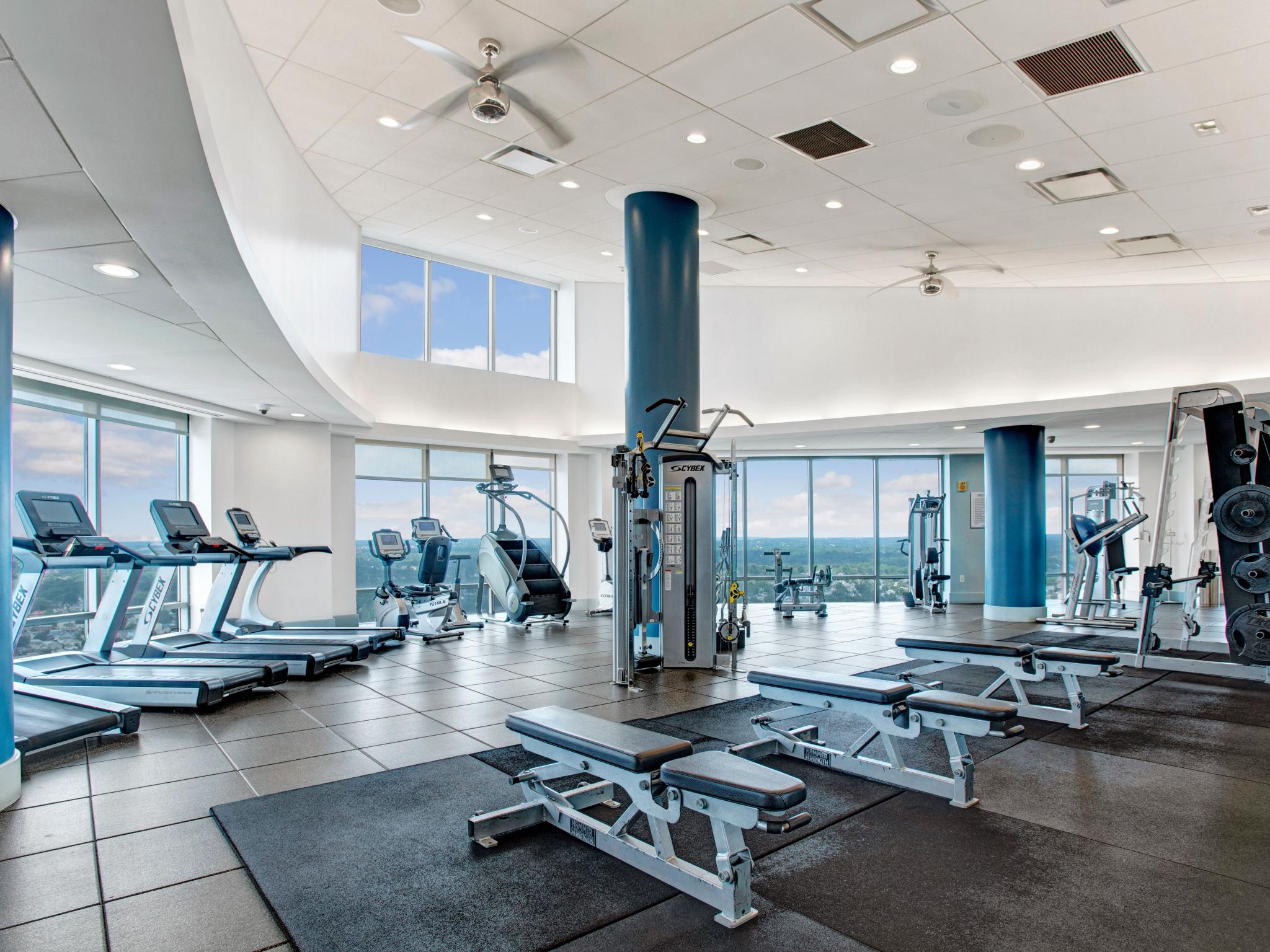 Spacious fitness center at Skyline New Rochelle, featuring state-of-the-art gym equipment, large windows with stunning skyline views, and a modern design.